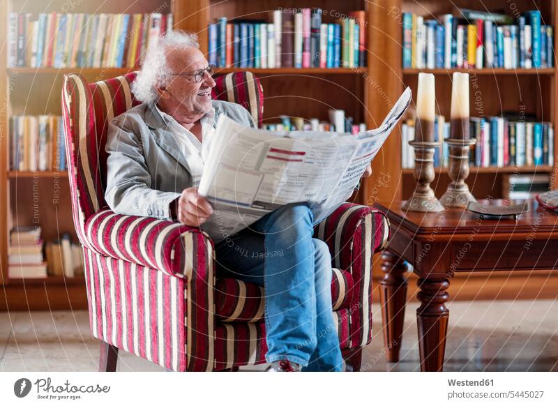 Älterer Mann sitzt in der Bibliothek und liest Zeitung sitzen sitzend Senior ältere Männer älterer Mann Senioren Altersheim Altenheim Seniorenheim lesen Lektüre
