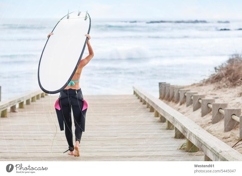 Frau geht mit Surfbrett zum Strand weiblich Frauen tragen transportieren Surfen Surfing Wellenreiten Beach Straende Strände Beaches Surfbretter surfboard