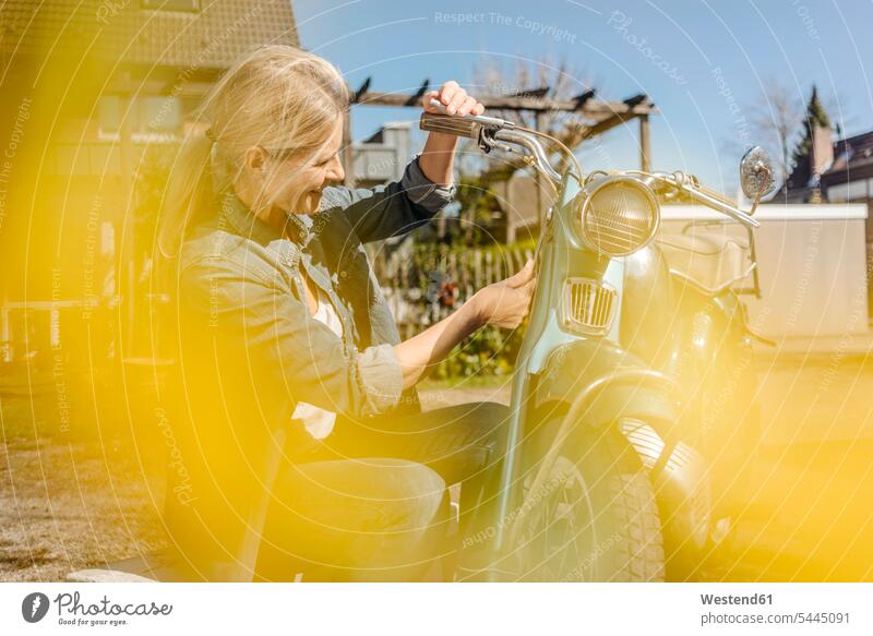 Lächelnde Frau mit Oldtimer-Motorrad weiblich Frauen Motorräder lächeln Erwachsener erwachsen Mensch Menschen Leute People Personen Kraftfahrzeug Verkehrsmittel