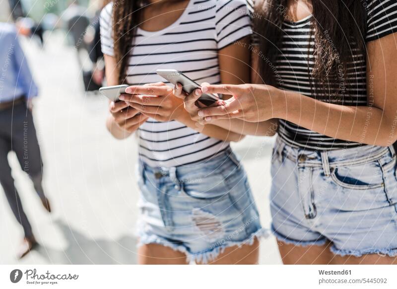 Zwei junge Frauen mit Mobiltelefonen in der Stadt Freundinnen Handy Handies Handys Freunde Freundschaft Kameradschaft Telefon telefonieren Kommunikation