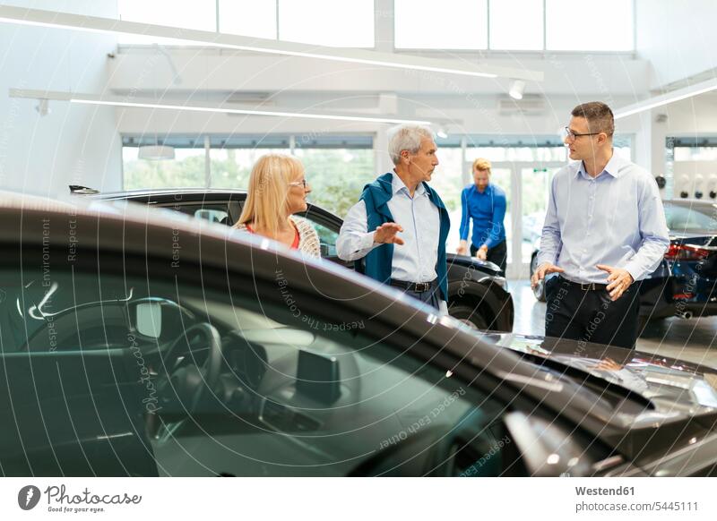 Verkäufer, der Kunden im Autohaus berät Kundin aussuchen auswählen verkaufen Wagen PKWs Automobil Autos beraten beratend Paar Pärchen Paare Partnerschaft