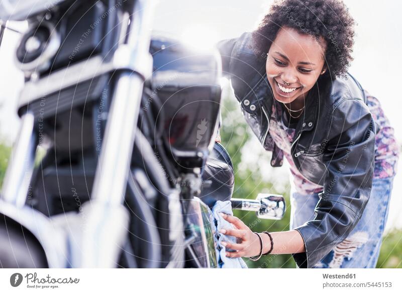 Junge Frau reinigt ihr Motorrad lächeln putzen reinigen Motorräder weiblich Frauen Kraftfahrzeug Verkehrsmittel KFZ Erwachsener erwachsen Mensch Menschen Leute