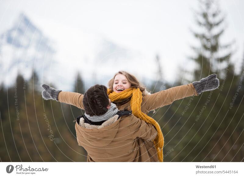 Glückliches junges Paar amüsiert sich im Winterwald Pärchen Paare Partnerschaft winterlich Winterzeit Mensch Menschen Leute People Personen Natur glücklich