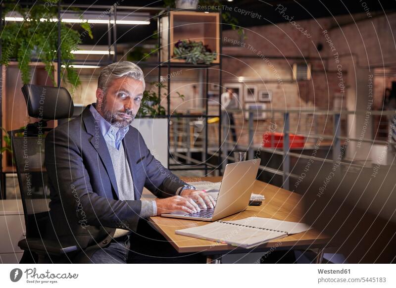 Ein reifer Geschäftsmann, der in einem modernen Büro arbeitet und einen Laptop benutzt Notebook Laptops Notebooks Schreibtisch Arbeitstisch Schreibtische