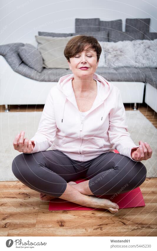 Ältere Frau, die zu Hause Yoga praktiziert weiblich Frauen sitzen sitzend sitzt Schneidersitz Yoga-Übungen Yogauebungen Yogaübungen Jogauebung Jogauebungen