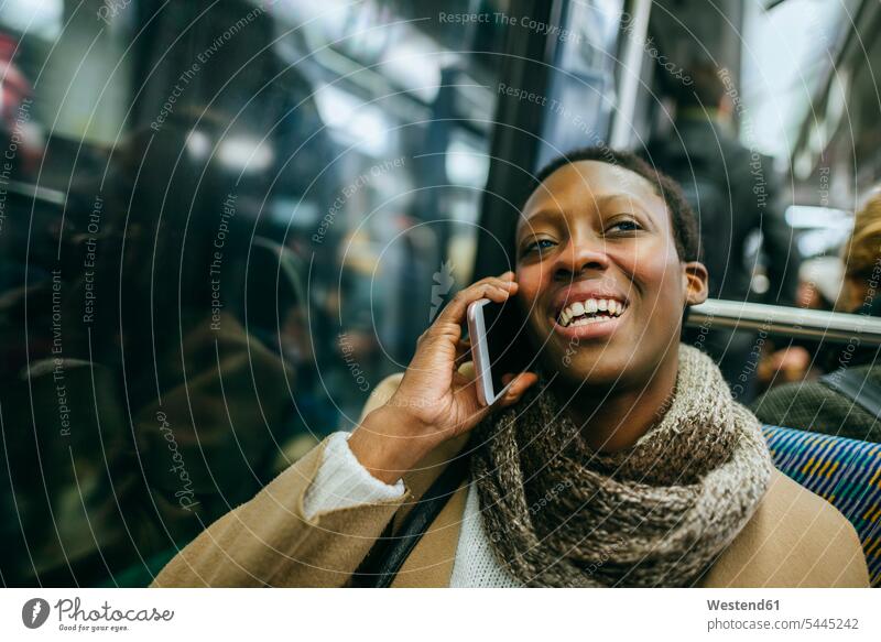 Porträt einer lächelnden jungen Frau am Telefon in der U-Bahn weiblich Frauen Portrait Porträts Portraits telefonieren anrufen Anruf telephonieren Erwachsener