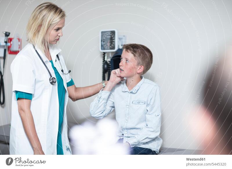Weibliche Pädiaterin untersucht Jungen mit einem Otoskop Stethoskop Stethoskope Kinderarzt Kinderärzte Kinderaerzte zuhören zuhörend Buben Knabe Knaben männlich