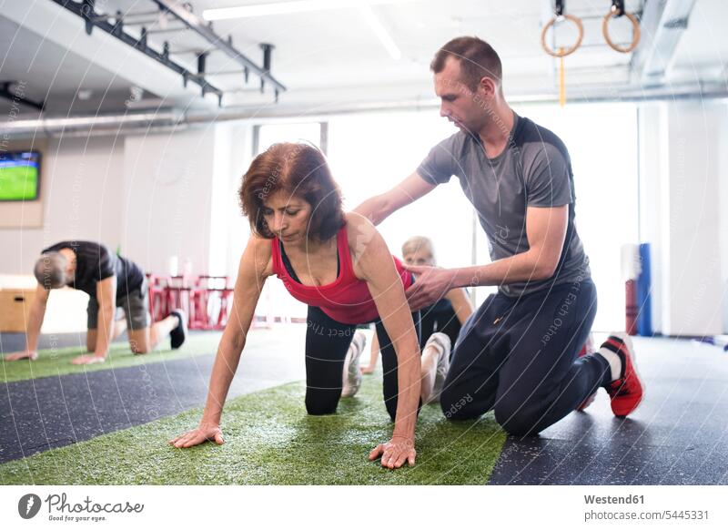Persönlicher Trainer unterstützt ältere Frau im Fitnessstudio trainieren Senioren alte Fitnessclubs Fitnessstudios Turnhalle Erwachsene erwachsen Mensch