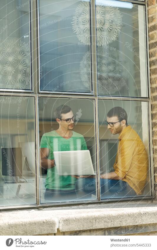 Junge Berufstätige am Fenster mit Laptop sitzen sitzend sitzt Kreative Kreativer Kreativer Beruf Laptop benutzen Laptop benützen Fensterbank Fensterbrett