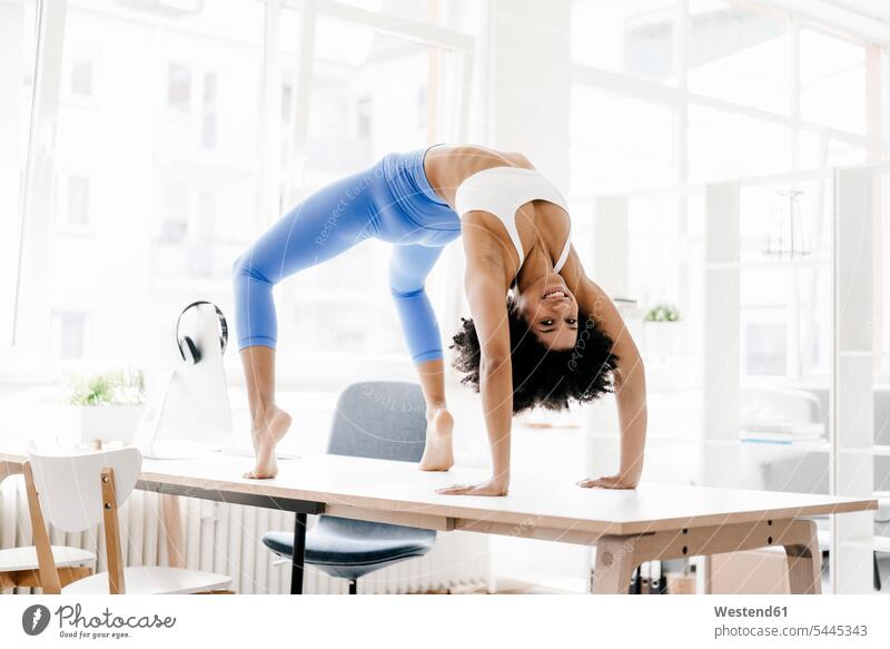 Junge Frau praktiziert Yoga auf ihrem Schreibtisch Training trainieren Online fit Laptop Notebook Laptops Notebooks lernen üben ausüben Übung weiblich Frauen