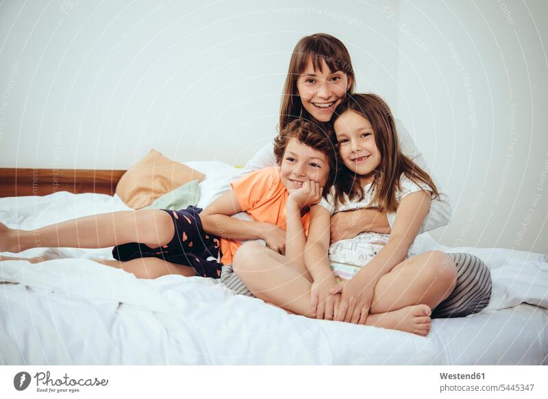 Glückliche Mutter mit ihrer Tochter und ihrem Sohn im Bett Familie Familien Portrait Porträts Portraits Mami Mutti Mütter Mama Betten lächeln Mensch Menschen