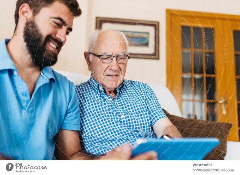 Erwachsener Enkel lehrt seinen Großvater, Tabletten zu verwenden Opa Großpapa Großpapas Opas Opi Großväter Opis Enkelsöhne Enkelsohn Tablet Computer Tablet-PC