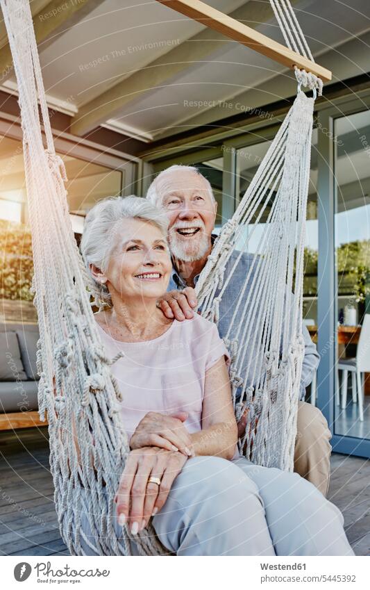 Älteres Ehepaar auf Terrasse, Frau sitzt in Hängematte Terrassen Paar Pärchen Paare Partnerschaft Älter werden Aelter werden Altern Hängematten Gemeinsam
