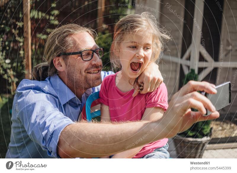 Vater und Tochter machen ein Selfie im Garten Handy Mobiltelefon Handies Handys Mobiltelefone Papas Väter Vati Vatis Papis Selfies Töchter Gärten Gaerten