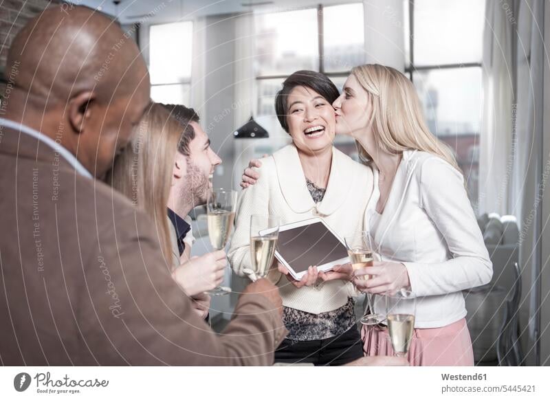 Glückliche Frau zeigt Freunden mit Champagnergläsern zu Hause Tablette Sekt Zuhause daheim feiern Tablet Computer Tablet-PC Tablet PC iPad Tablet-Computer