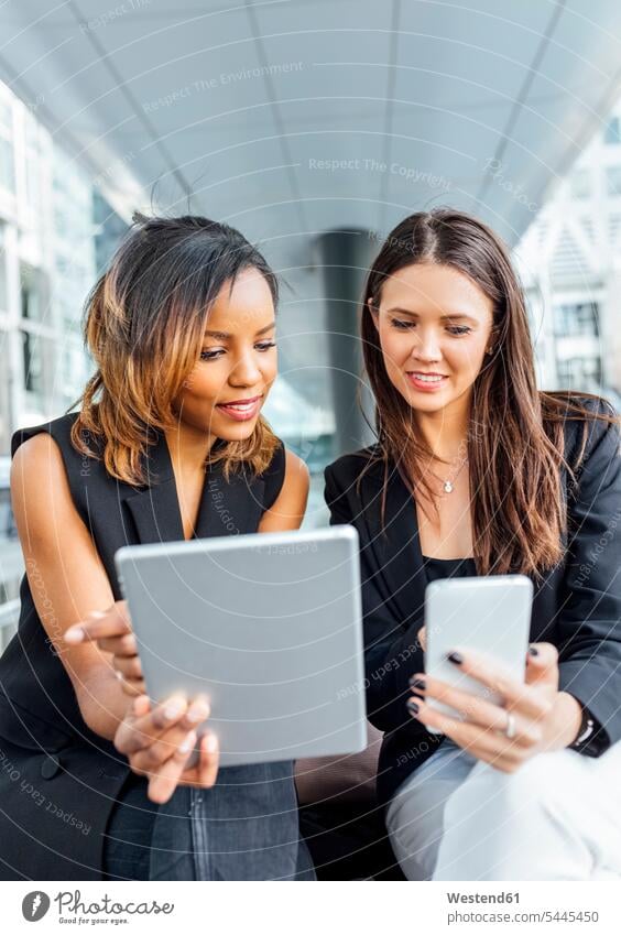 Zwei Geschäftsfrauen arbeiten mit Smartphone und Tablet in der Stadt Businesswomen Businessfrauen Businesswoman Frau weiblich Frauen Kollegin Kolleginnen Handy