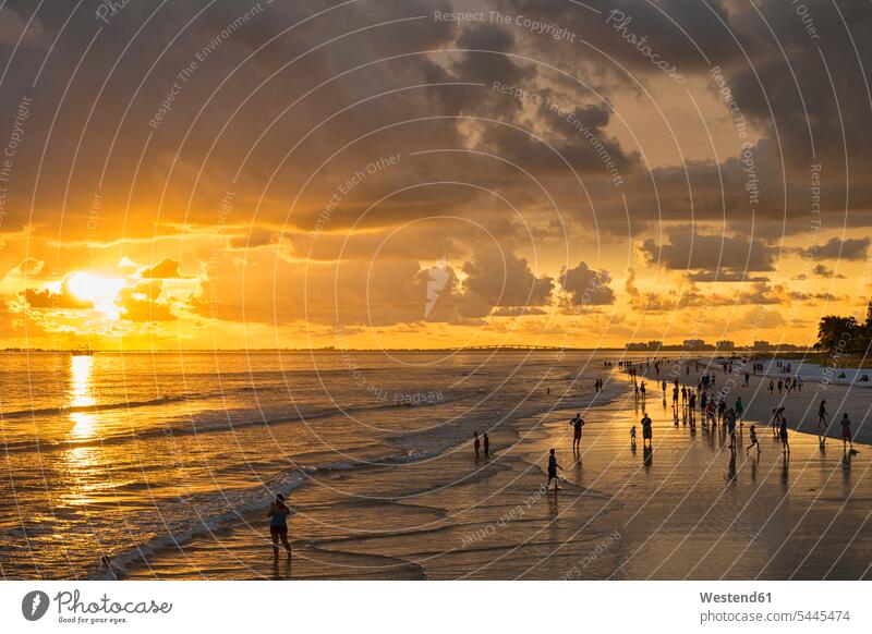 USA, Florida, Fort Myers, Silhouetten von Fort Myers Beach und Touristen mit einer riesigen Regenwolke darüber bei Sonnenuntergang Küste Küstenlandschaft Gruppe