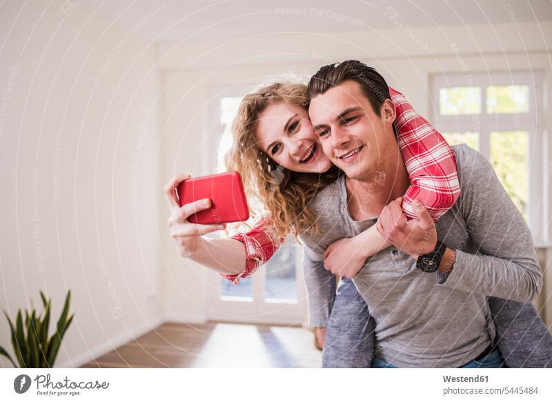 Glückliches junges Paar im neuen Haus, das ein Selfie macht Spaß Spass Späße spassig Spässe spaßig Pärchen Paare Partnerschaft Handy Mobiltelefon Handies Handys