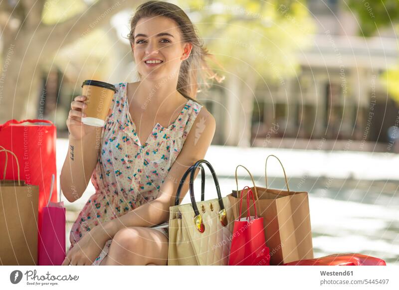 Lächelnde junge Frau mit Einkaufstasche und Kaffee zum Mitnehmen lächeln glücklich Glück glücklich sein glücklichsein Shopping einkaufen shoppen Einkaufen