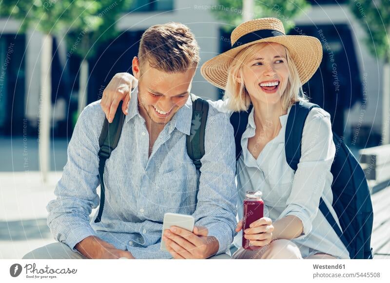 Zwei Touristen amüsieren sich in der Stadt Paar Pärchen Paare Partnerschaft Mensch Menschen Leute People Personen Smartphone iPhone Smartphones lachen Rucksack