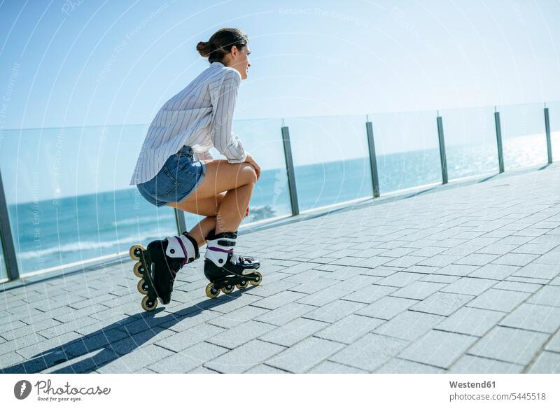 Junge Frau mit Inline-Skates auf der Strandpromenade an der Küste weiblich Frauen Inlineskates Inline skates inline skate Inliner Erwachsener erwachsen Mensch