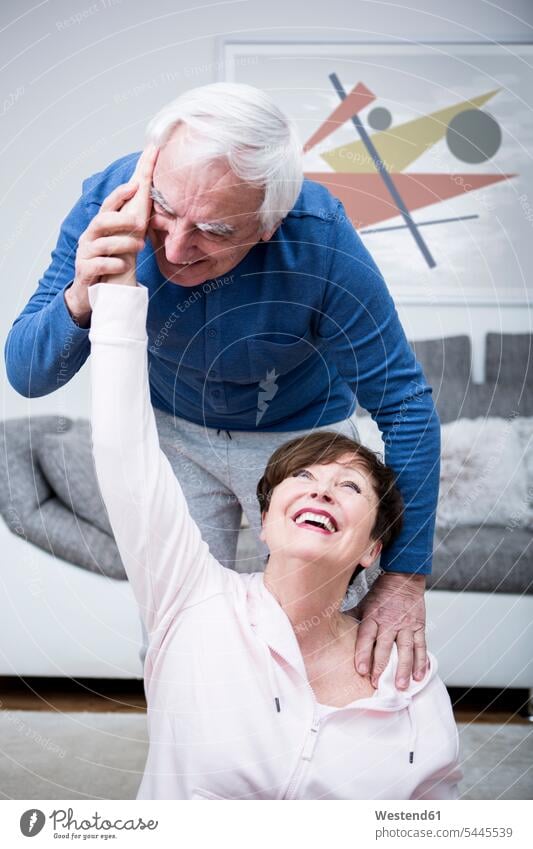 Älteres Ehepaar trainiert gemeinsam zu Hause Europäer Kaukasier Europäisch kaukasisch Beweglichkeit Biegsamkeit beweglich Fitness Gesundheit gesund Aktivität
