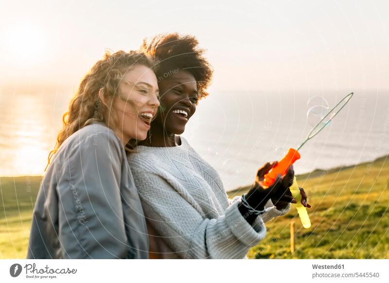 Zwei beste Freunde machen bei Sonnenuntergang Seifenblasen im Freien Freundinnen glücklich Glück glücklich sein glücklichsein Frau weiblich Frauen Freundschaft