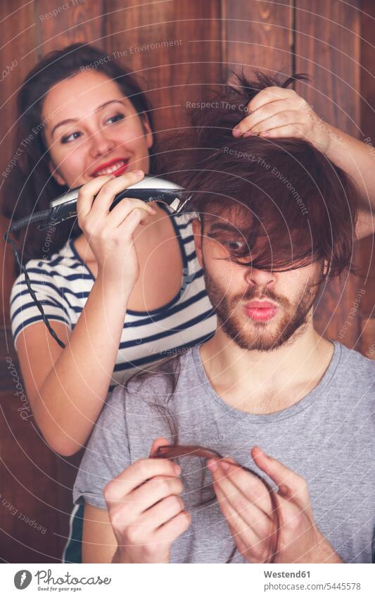 Junger Mann lässt sich von seiner Freundin mit einer Haarschneidemaschine die Haare schneiden Mensch Menschen Leute People Personen schauen schauend anschauen