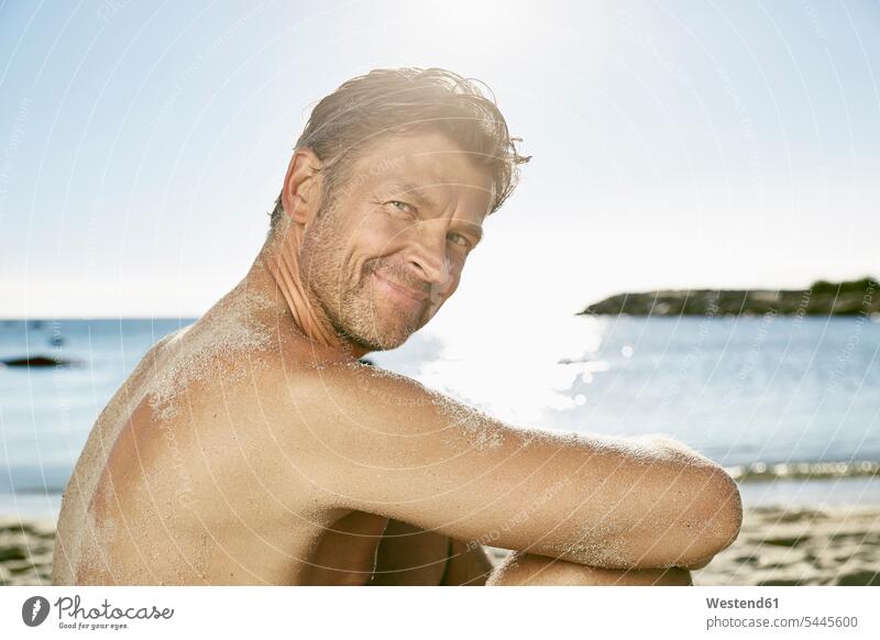 Porträt eines lächelnden Mannes beim Entspannen am Strand Meer Meere Portrait Porträts Portraits Männer männlich Beach Straende Strände Beaches Gewässer Wasser