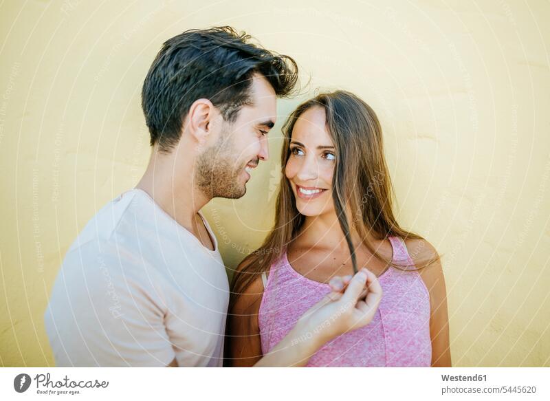 Junges Paar schaut sich verliebt an der gelben Wand an ansehen glücklich Glück glücklich sein glücklichsein Pärchen Paare Partnerschaft lächeln schauen sehend