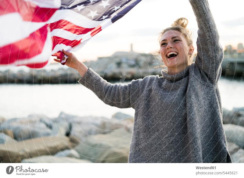 Porträt einer lachenden jungen Frau mit wehender US-amerikanischer Flagge weiblich Frauen amerikanische Flagge Erwachsener erwachsen Mensch Menschen Leute