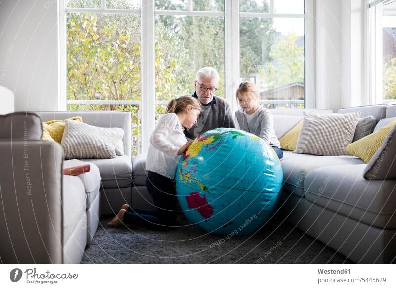 Zwei Mädchen und Großvater mit Globus im Wohnzimmer Kind Mensch Wohnen Zimmer Großeltern Familie erklären Fenster Fürsorge Gemeinsam Zuhause Geografie Enkelin