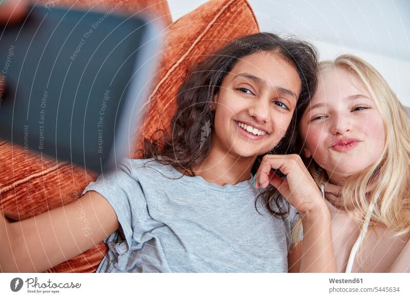 Zwei glückliche Mädchen auf der Couch machen ein Selfie Selfies Freundinnen Handy Mobiltelefon Handies Handys Mobiltelefone weiblich Freunde Freundschaft