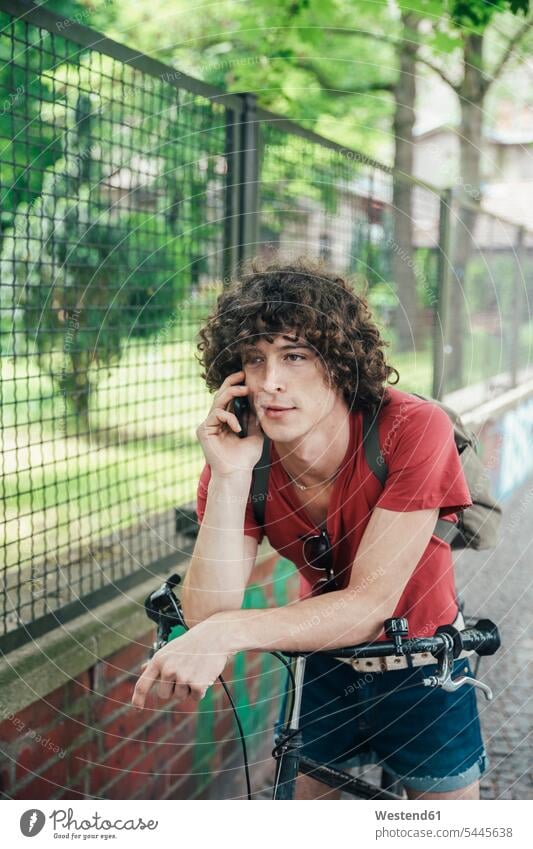 Junger Mann mit Fahrrad am Telefon Handy Mobiltelefon Handies Handys Mobiltelefone telefonieren anrufen Anruf telephonieren Männer männlich Bikes Fahrräder