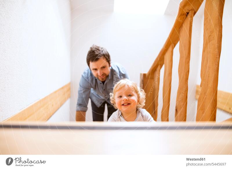 Vater mit kleinem Jungen auf Holztreppe zu Hause Baby Babies Babys Säuglinge Kind Kinder Treppe Treppenaufgang Papas Väter Vati Vatis Papis lächeln Zuhause