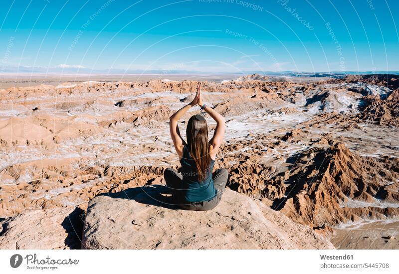 Chile, Atacama-Wüste, Rückenansicht einer Frau, die auf einem Felsen Yoga praktiziert weiblich Frauen Lotussitz Lotusposition Lotuspositionen Erwachsener