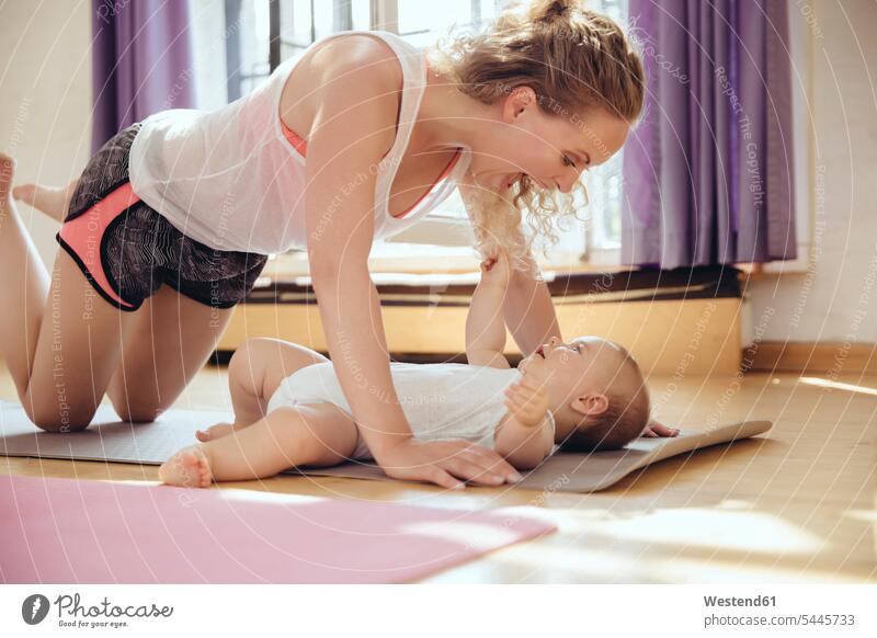 Mutter spielt beim Training mit ihrem Baby auf der Yogamatte Babies Babys Säuglinge Kind Kinder trainieren Yoga-Übungen Yogauebungen Yogaübungen Jogauebung