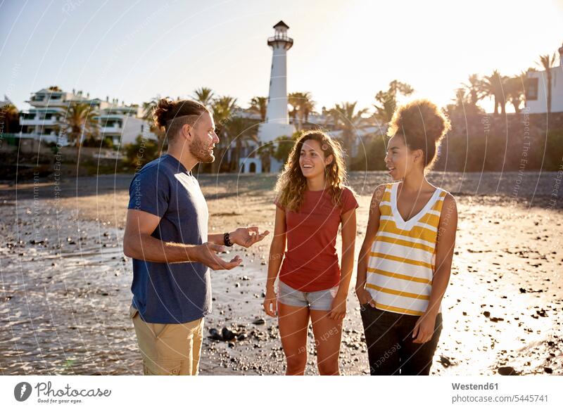 Spanien, Kanarische Inseln, Gran Canaria, drei Freunde entspannen gemeinsam am Strand Beach Straende Strände Beaches Freundschaft Kameradschaft sprechen reden