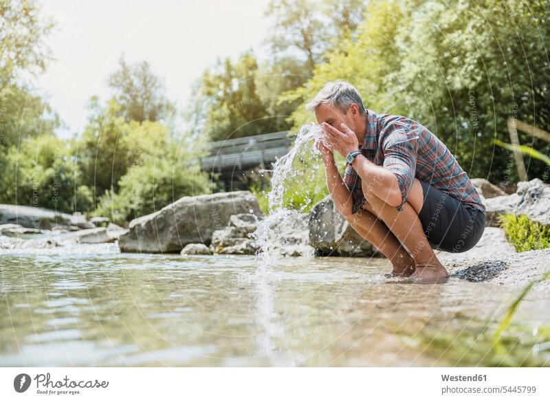 Wanderer macht Pause am Flussufer und wäscht sich das Gesicht wandern Wanderung Wasser Mann Männer männlich Erwachsener erwachsen Mensch Menschen Leute People