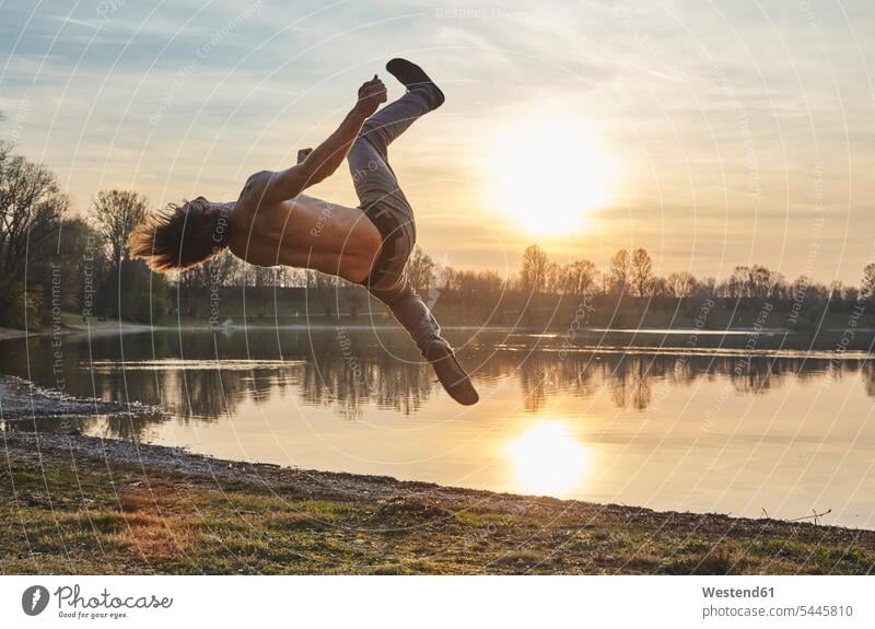 Deutschland, Bayern, Feldkirchen, Mann beim Parkour am Seeufer Männer männlich Seen Parcour springen hüpfen Erwachsener erwachsen Mensch Menschen Leute People