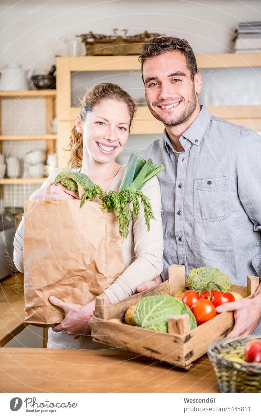 Lächelndes Paar mit Gemüsekiste in der Küche lächeln Pärchen Paare Partnerschaft Gemuese Küchen Mensch Menschen Leute People Personen Essen Food Food and Drink