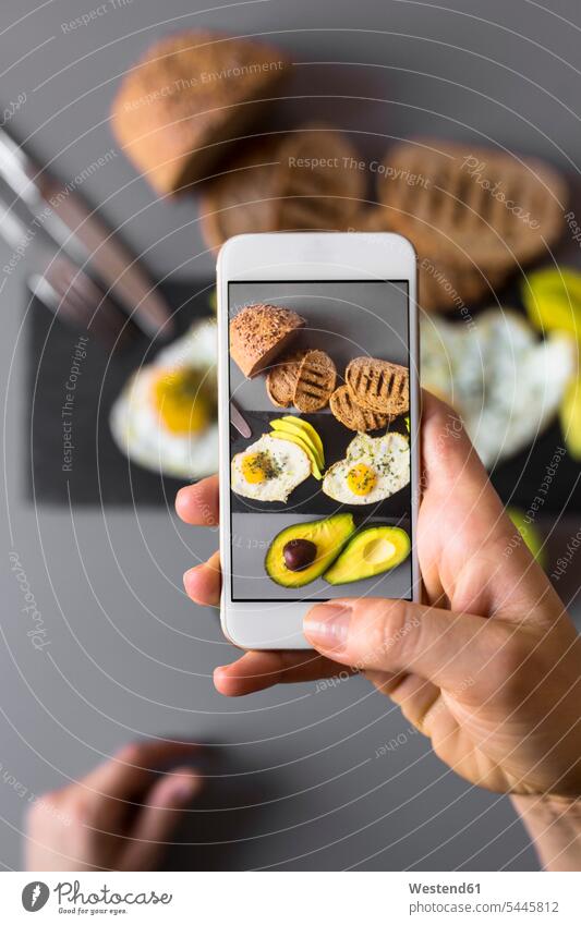 Handaufnahme eines Smartphone-Fotos vom Frühstück mit Avocados und Eiern Handy Mobiltelefon Handies Handys Mobiltelefone Teilen Sharing Drahtlose Technologie
