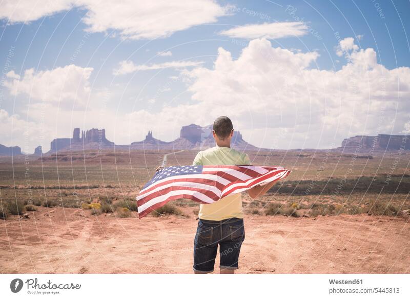 USA, Utah, Rückenansicht eines Mannes mit amerikanischer Flagge beim Blick auf Monument Valley Männer männlich amerikanische Flagge Erwachsener erwachsen Mensch