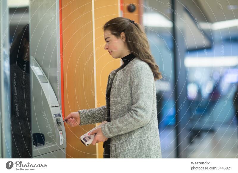Junge Frau in einem Einkaufszentrum am Geldautomaten Shopping Mall weiblich Frauen benutzen Bancomaten Geldausgabeautomat Bankomaten Geldausgabeautomaten