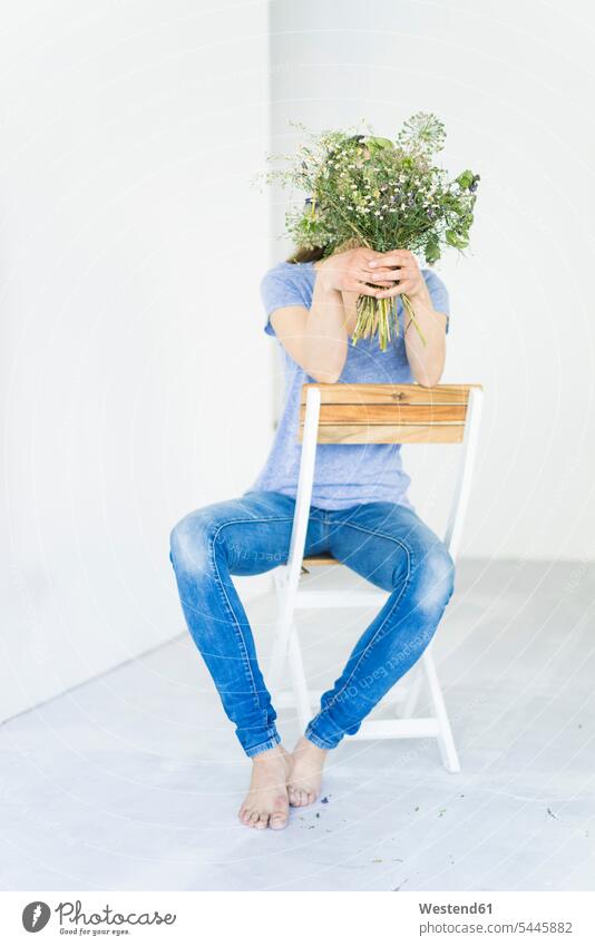 Frau sitzt auf einem Stuhl und hält einen Blumenstrauss vor ihr Gesicht halten Blumenstrauß Bouquet Blumensträusse Blumensträuße weiblich Frauen Stuehle Stühle