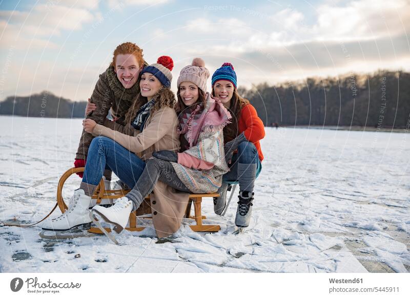 Freunde amüsieren sich mit Schlitten auf dem gefrorenen See glücklich Glück glücklich sein glücklichsein lachen Rodelschlitten positiv Emotion Gefühl Empfindung