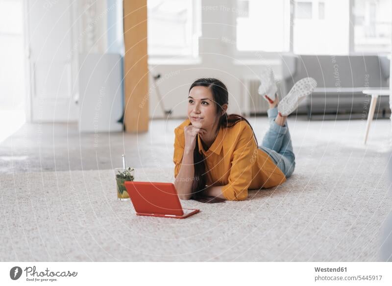 Junge Frau, die einen Laptop benutzt, auf dem Boden liegt und nachdenkt weiblich Frauen jung Eistee Eistees Teppich Teppiche liegen liegend arbeiten Arbeit