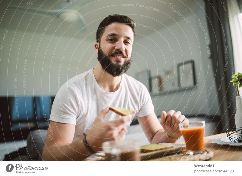 Porträt eines jungen Mannes beim Frühstück Toast Toastbrote Toasts Männer männlich lächeln Brot Brote Essen Food Food and Drink Lebensmittel Essen und Trinken