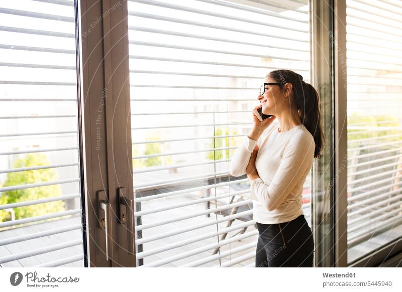 Frau am Telefon, die aus dem Fenster schaut telefonieren anrufen Anruf telephonieren weiblich Frauen Telefon benutzen Erwachsener erwachsen Mensch Menschen