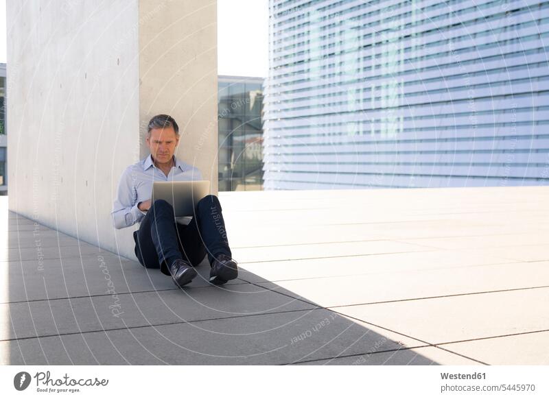 Geschäftsmann benutzt Laptop im Freien sitzen sitzend sitzt Notebook Laptops Notebooks Businessmann Businessmänner Geschäftsmänner arbeiten Arbeit Computer